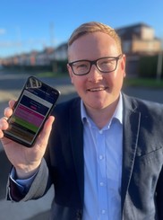 Councillor Dominic Beck holding his phone