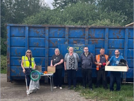 litter pickers stood in front of skip