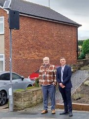 two men stood beneath speed sign