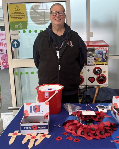 Photograph of Doug who is stood smiling in front of a poppy stall