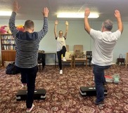 Photograph shows tenants doing exercises with an instructor 