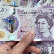 A woman's hand holding a £20 note