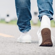A person, in white trainers and jeans, walking away from the camera