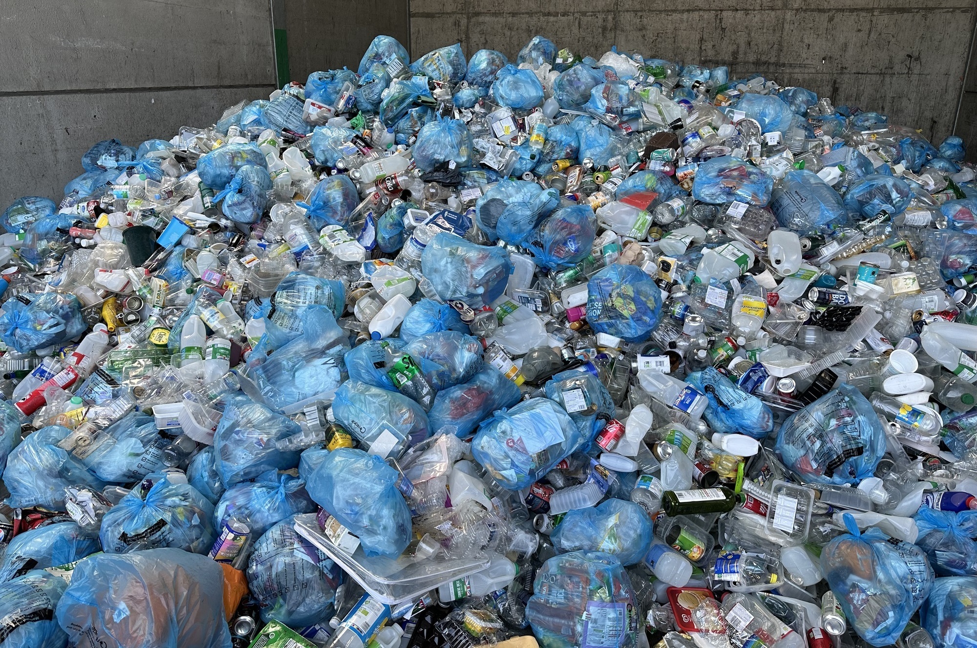 A large amount of plastic for recycling, which includes full blue bags used for collecting soft plastics