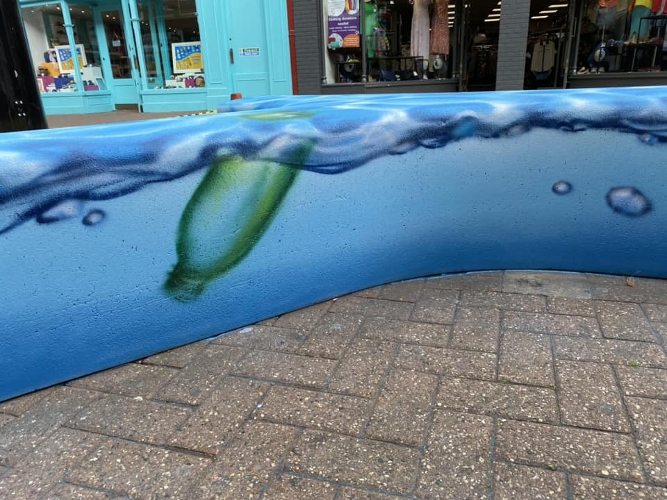Local artist Sam Gaden of Aerosol Art showing off his ocean plastic-themed spray painting design on one of the benches, courtesy of GoCreate Taunton