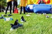 Summer play day scene with scattered shoes on the grass and a bouncy castle in the background by Skylar Zilka from Unsplash