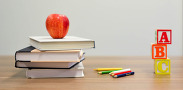 An apple on top of a stack of books with pencils and ABC Blocks