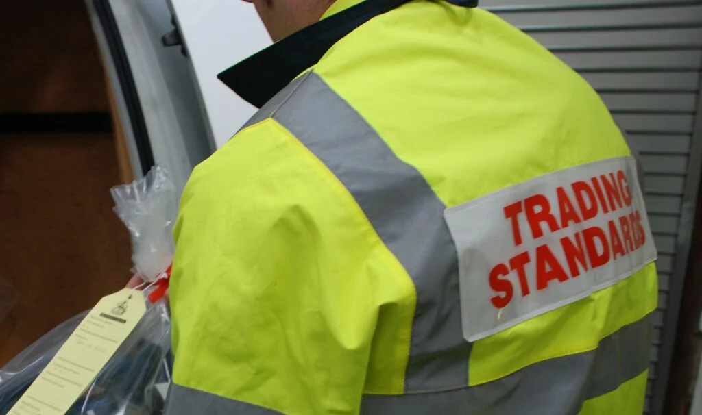 Trading Standards Officer wearing a hi-vis jacket loading a sealed evidence bag into a van