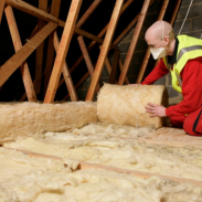 A person insulating a loft space wearing a mask