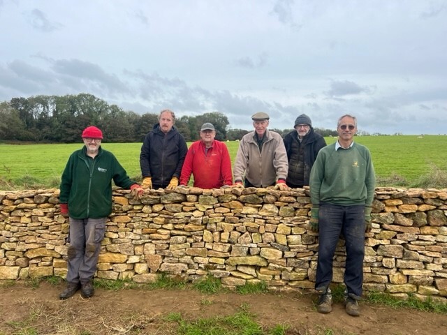 Geoff Rowland and some of the drystone walling volunteers next to a dry stone wall at Ham Hill