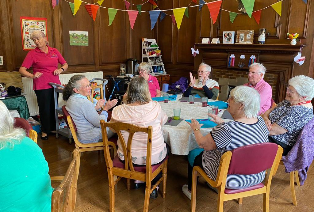 Group of elderly people sitting around a table at a dementia charity event by Reminiscence Learning.