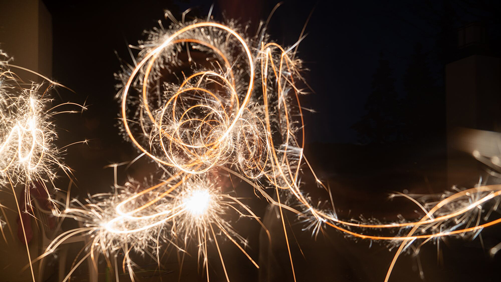 Stock image of sparklers leaving light trails in the sky by Daniel Gregoire from unsplash.