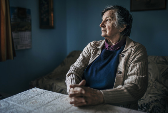 72 year old Audrey, sat at a table in her living room looking cold and worried.