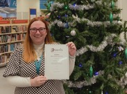 Christina Evans, accepting her Award whilst stood in front of a Christmas tree in a Somerset library.