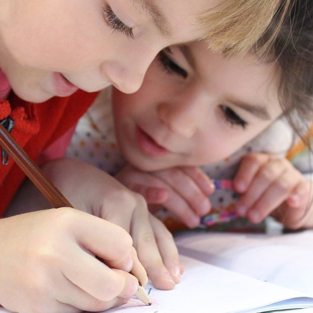 Two children drawing a picture together.