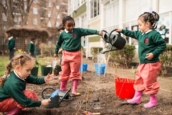 Infant school children watering newly planted trees.