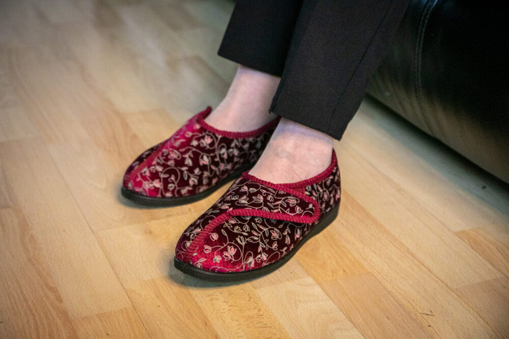 A pair of non-slip slippers being worn by an elderly woman.