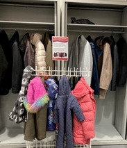 Rail of donated coats in a library.