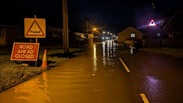 A flooded road and warning signs in Somerset the early morning after Storm Henk.