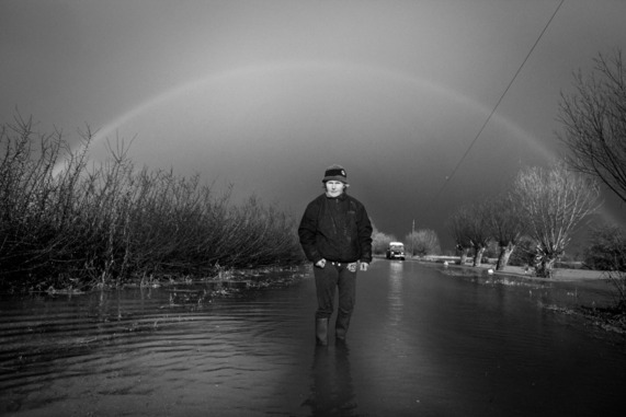 Flood victim, Christine Gray, stood in the middle of a flooded Somerset road with a rainbow above.