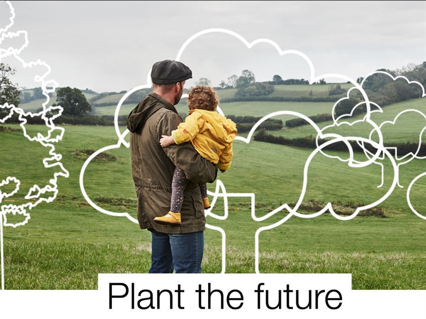 put down roots campaign image. Man looking across open countryside holding a small child