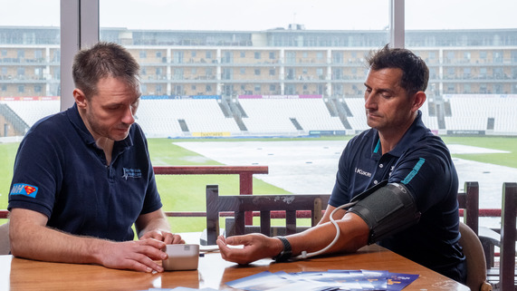 Somerset Cricket Head Coach, Jason Kerr, having his blood pressure taken by Dr Tim Norbury from Taunton Vale Healthcare.