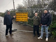 3 people pointing to a yellow 'pedestrian access only' sign on a metal fence at Cleeve Opening.