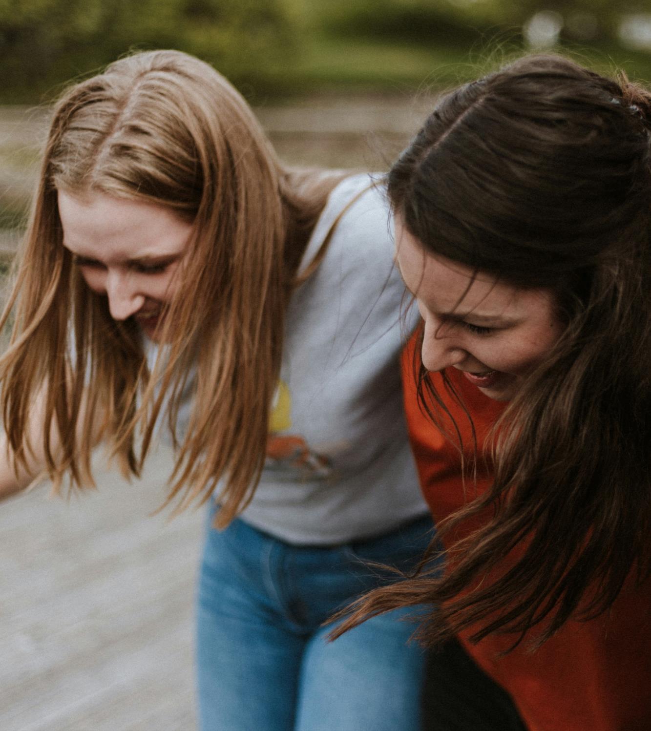 Two adolescent girls laughing together.