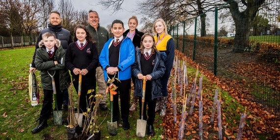 A group of adults and children gathered to plant new trees
