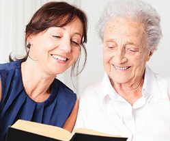 Younger woman helping older woman with a book.