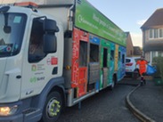 A waste operative collecting recycling with a Somerset branded recycling lorry.