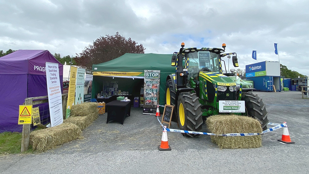 A parked tractor with advertising outside a tented exhibition display at an outdoor farming expo.