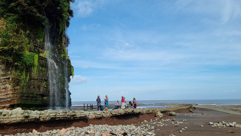 A group of family and friends having a picnic under a waterfall on the Quantocks and Coast walk.