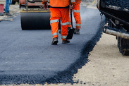 Roadworkers resurfacing a road with hot tarmac.