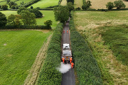 Aerial view of a road surface dressing lorry and crew in action on a country road.