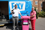 Fixy staff posing in front of their van, with a drill to be recycled in a pink wheelie bin.