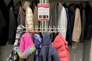 Rail of donated coats in a library.