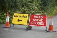 Traffic cones with 'diversion' and 'road ahead closed' signs on a road.