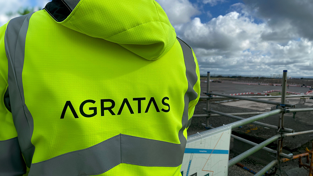 Agratas staff member wearing a Hi-Viz atop scaffolding, overlooking a development site.