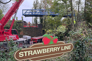 Photo of 15 foot bridge being lifted into Shepton Mallet with Strawberry Line sign in foreground.