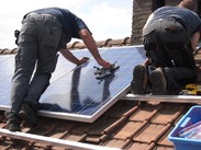 two workman on a tiled roof installing solar panels