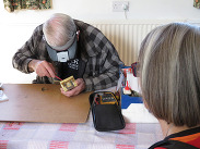 A volunteer repairer fixes a clock.