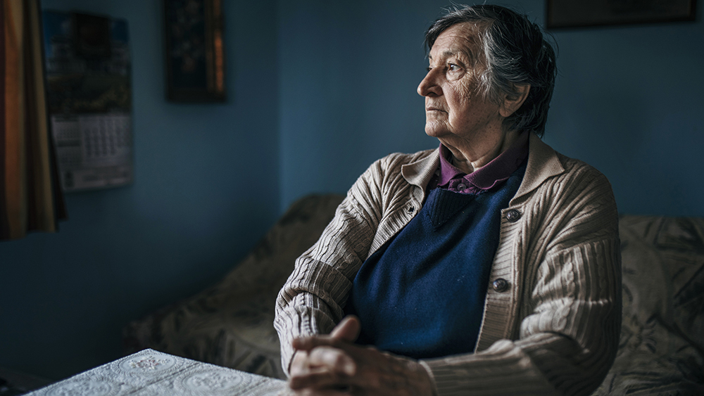 72 year old Audrey, sat at a table in her living room looking cold and worried.
