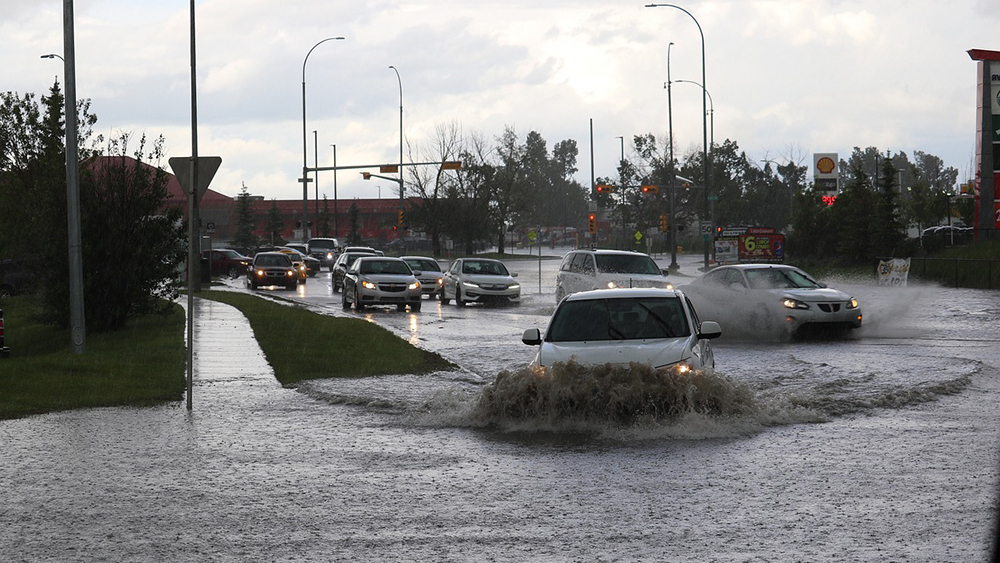 Streetscape of cars driving through floodwater.