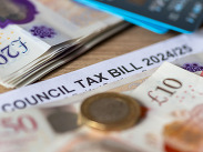 A close up of a United Kingdom local authorities Council Tax bill with bank notes, Pound coin and bank cards.