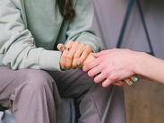A person holding another persons hands in a show of support.
