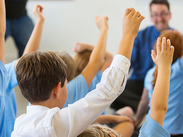 A group of children holding their hands up in a classroom.