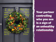 Christmas wreath on a door scribbled with domestic abusive-themed messages.