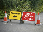 Traffic cones with 'diversion' and 'road ahead closed' signs on a road.