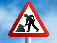 A roadworks sign against a sky blue background.